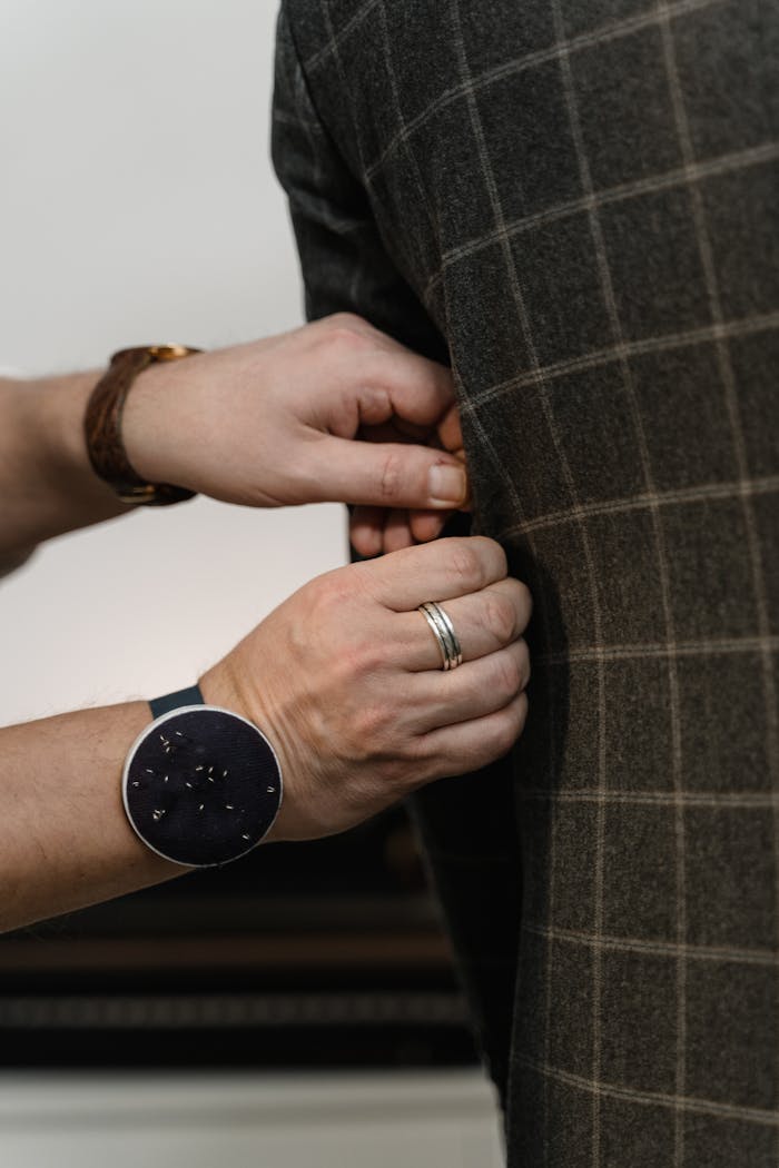 Close-up of a tailors hands adjusting a suit jacket showing craftsmanship and detail.